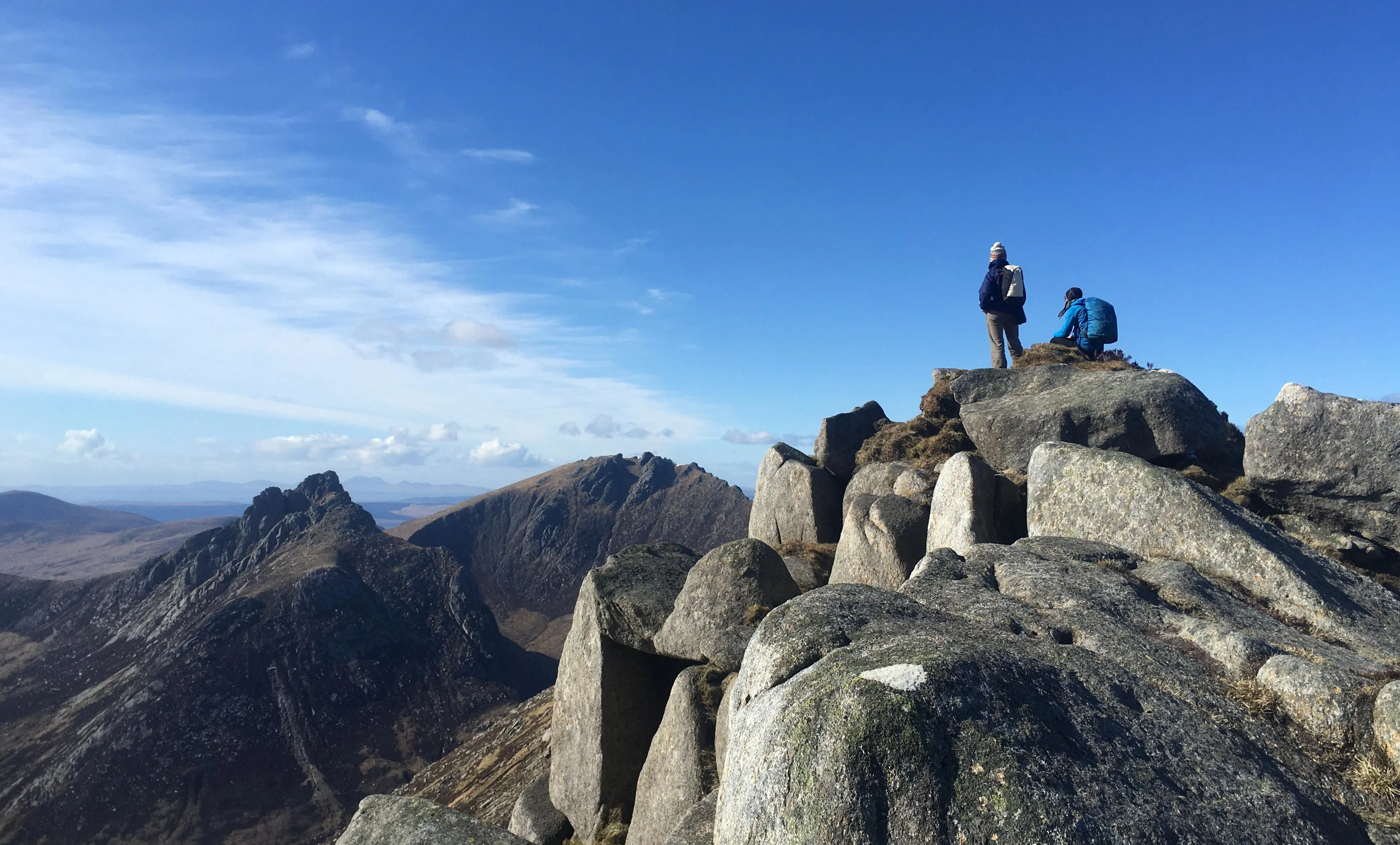 Two hill climbers enjoy the view from the top of a crag