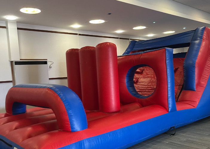 Red and blue inflatable obstacle course within a community hall