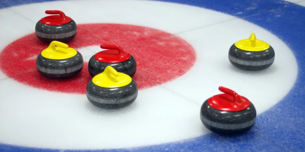 Red and yellow curling stones on ice rink