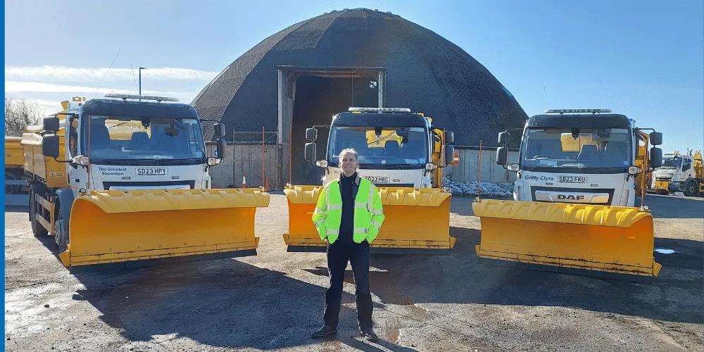 Councillor Tony Gurney standing in front of three snow ploughs