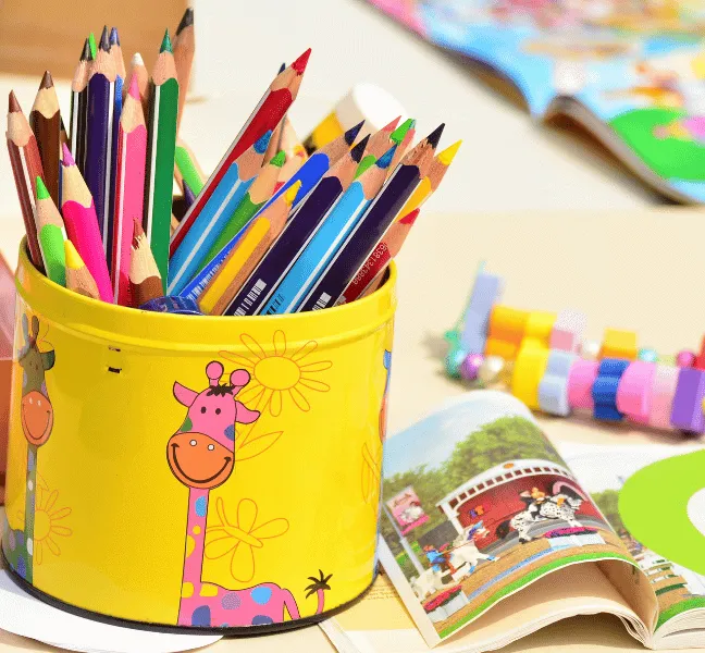 A tub of coloured pencils sitting next to an open children's book